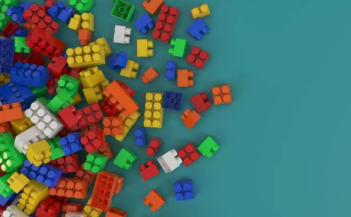 kolorowe klocki LEGO rozrzucone po lewej stronie na tle morskim