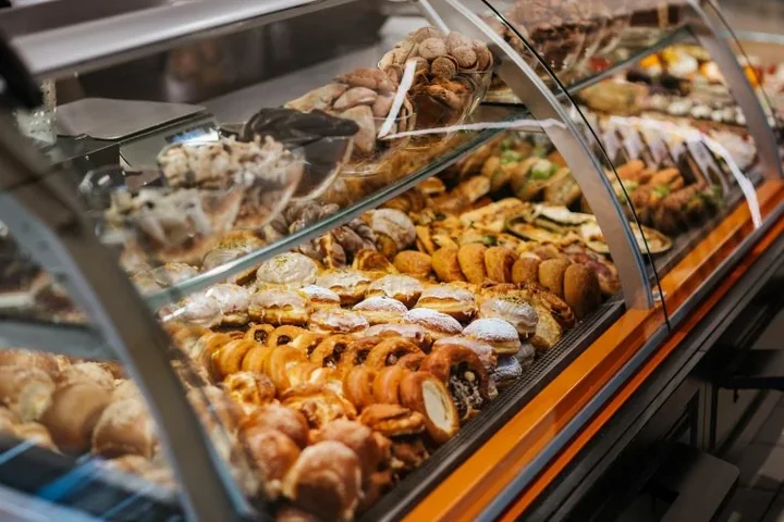 Na zdjęciu kanapki i słodkie przekąski (drożdzówki) w witrynie