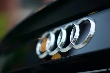 Zbliżenie na chromowane logo Audi z czterema pierścieniami na czarnym samochodzie