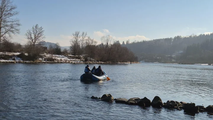 Osoby w pontonie spływają Dunajcem w zimowej scenerii
