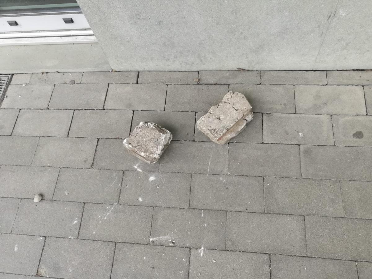 2 kostki brukowe za pomocą których dokonano uszkodzenia drzwi leżące przed wejściem do sklepu