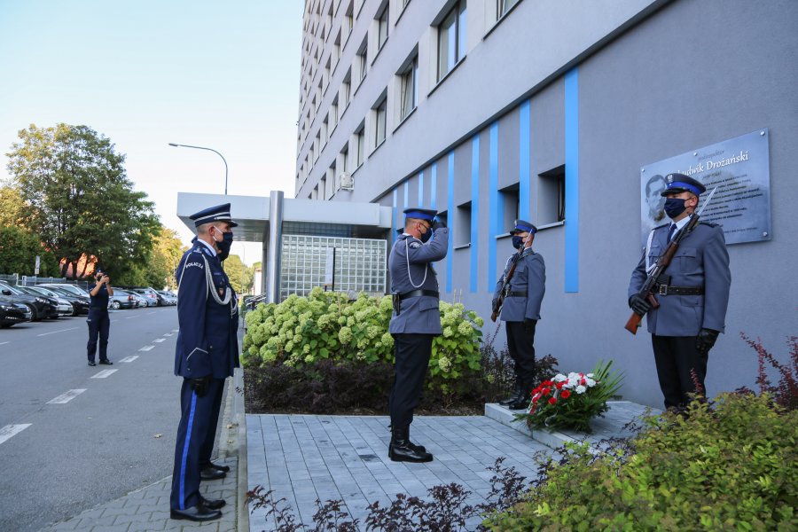 Policjanci oddają honory pod tablicą pamiątkową na terenie KWP w Krakowie