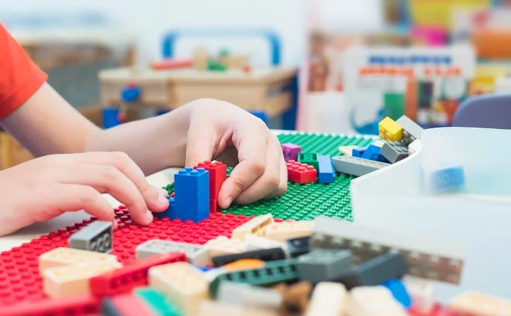 dziecięce ręce bawiące się kolorowymi klockami lego