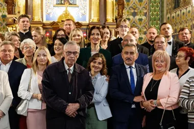 Grupa osób pozuje do pamiątkowego zdjęcia w bogato zdobionym wnętrzu kościoła.