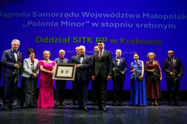 Grupa osób na scenie odbiera srebrną nagrodę „Polonia Minor” dla Oddziału SITK RP w Krakowie.