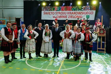 Grupa osób w strojach krakowskich i oficjalnych uczestniczy w Święcie Stroju Krakowskiego w gminie Zielonki.