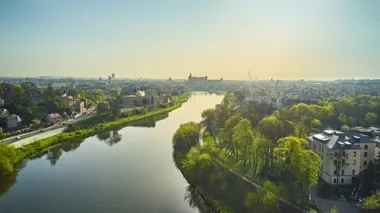 Widok z lotu ptaka na Wisłę płynącą przez Kraków, z Wawelem w tle, w słoneczny dzień wiosenny.