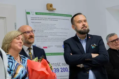 Grupa osób uczestniczy w uroczystym otwarciu żłobka samorządowego w Morawicy, w tle tablica informacyjna o inwestycji.